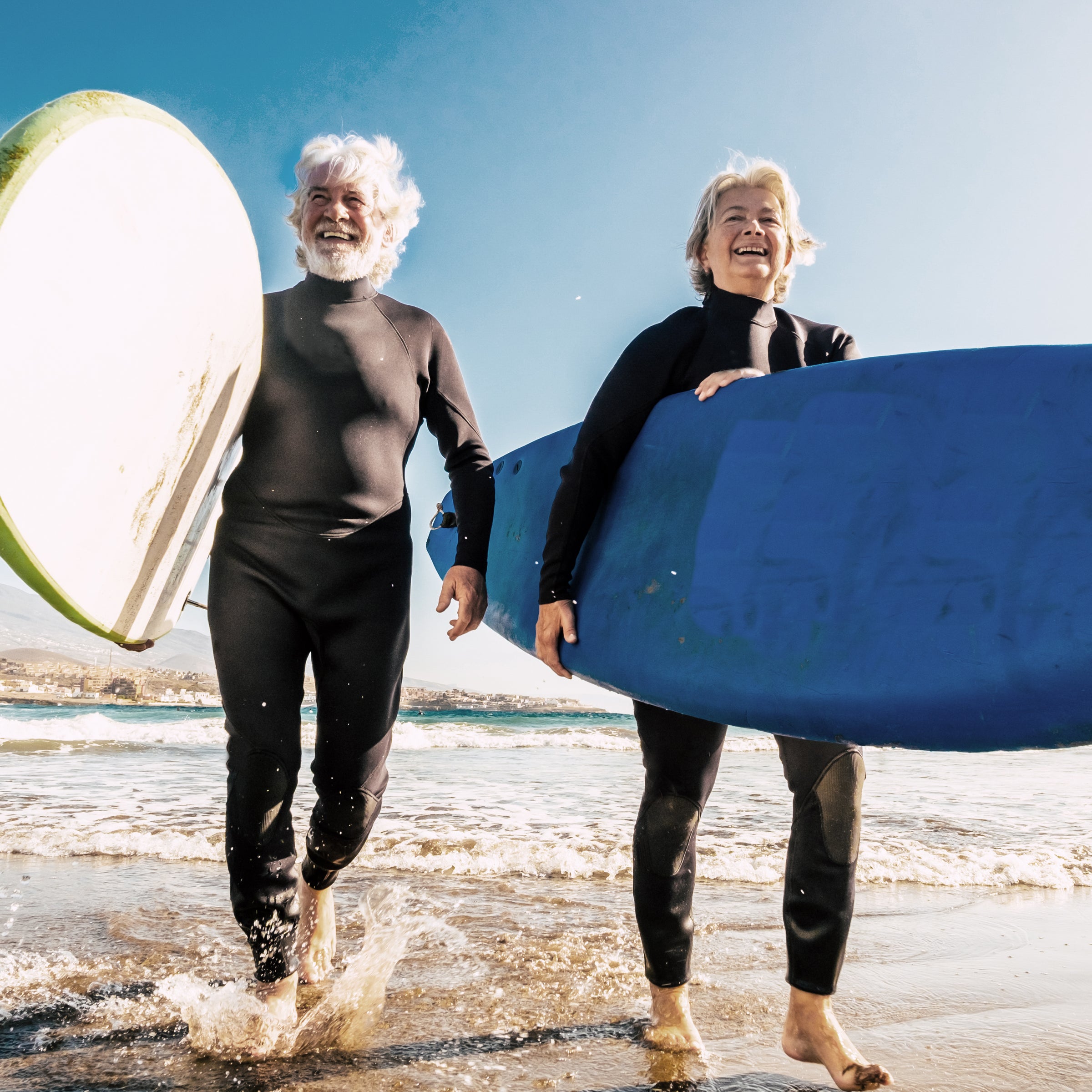 Deux personnes âgées avec des planches de surf au bord de la mer